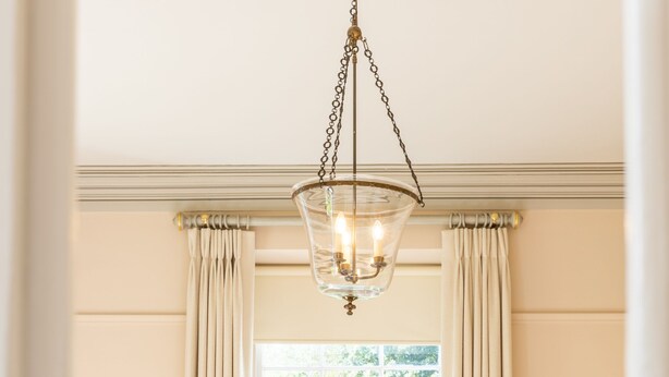 A dining room with a table set for two, a chandelier, and a window with curtains. - Luxury Country Estate in West Cork (Bandon)