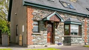 Une maison en pierre et en briques, dotée d’un toit en pente, de lucarnes et d’une cheminée.