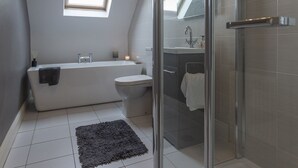 Une salle de bain moderne avec une douche à l’italienne, une baignoire sur pieds et une fenêtre.