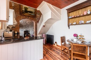 A kitchen with a stone fireplace, wooden ceiling, and a dining area with a table set for tea. - perfect for two people (Clarecastle)
