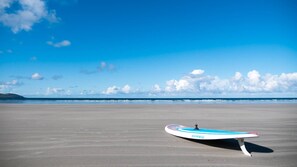 A beach with a single surfboard on the sand. - Luxurious 5 bedroomed home with sea view close to beach (Lettermacaward)