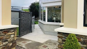 Un estrecho sendero que conduce a una casa con muro de piedra y puerta de metal.