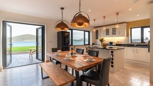 A modern kitchen with a dining area, large windows, and a view of the sea. - Luxury 4 bedroom holiday home overlooking the sea on Valentia Island (Farranreagh)