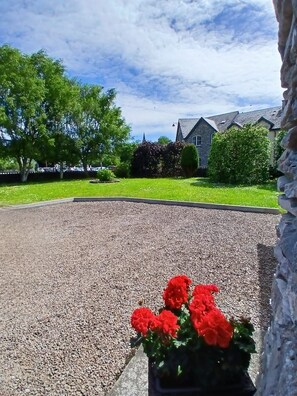 A gravel driveway leading to a house with a stone wall on the left.