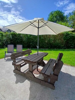 Une table de pique-nique avec un auvent, deux chaises et un banc, le tout installé dans un espace herbeux.