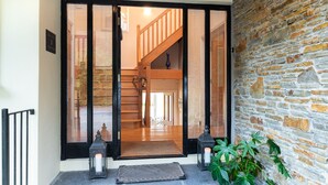 A wooden staircase leading to an upper floor, a stone wall, and a door with a black frame. - Stylish 4 bedroom home overlooking Kenmare Bay (Templenoe)