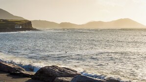 A coastal landscape with a lighthouse, rocky shoreline, and distant mountains. - Large house with adjoining cottage close to Waterville (Waterville)