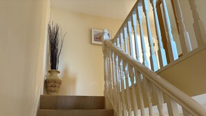 A staircase with white balusters and a woven carpet. - Holiday Home with view of Kenmare Bay Estuary (Kenmare)