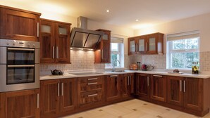 Una cucina moderna con mobili in legno, elettrodomestici in acciaio inossidabile, un'ampia finestra e uno schienale piastrellato.
