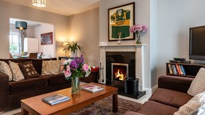 A cozy living room with a fireplace, a television, and a bookshelf.
