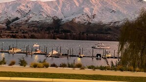 A marina with boats docked, a mountain range in the background, and a clear sky. - Central Wanaka Lakeside Condo (Wanaka)