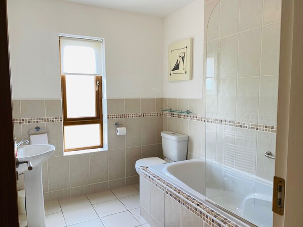 A bathroom with a bathtub, toilet, sink, and a window.