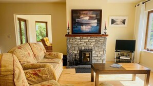 Una sala de estar con chimenea de piedra, un sofá, un televisor y un cuadro enmarcado.