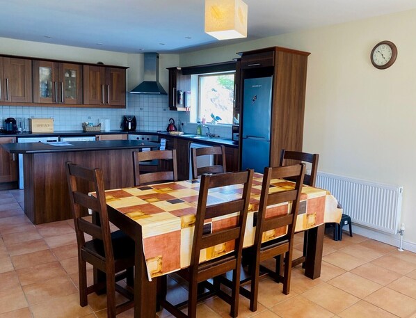 A modern kitchen with wooden cabinets, a central island, and a dining area with a checkered tablecloth.