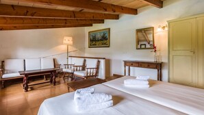 A hotel room with two beds, a sofa, a wooden table, a desk, a lamp, and a painting on the wall. - Villa Can Mart By SunVillas Mallorca (Pollença)
