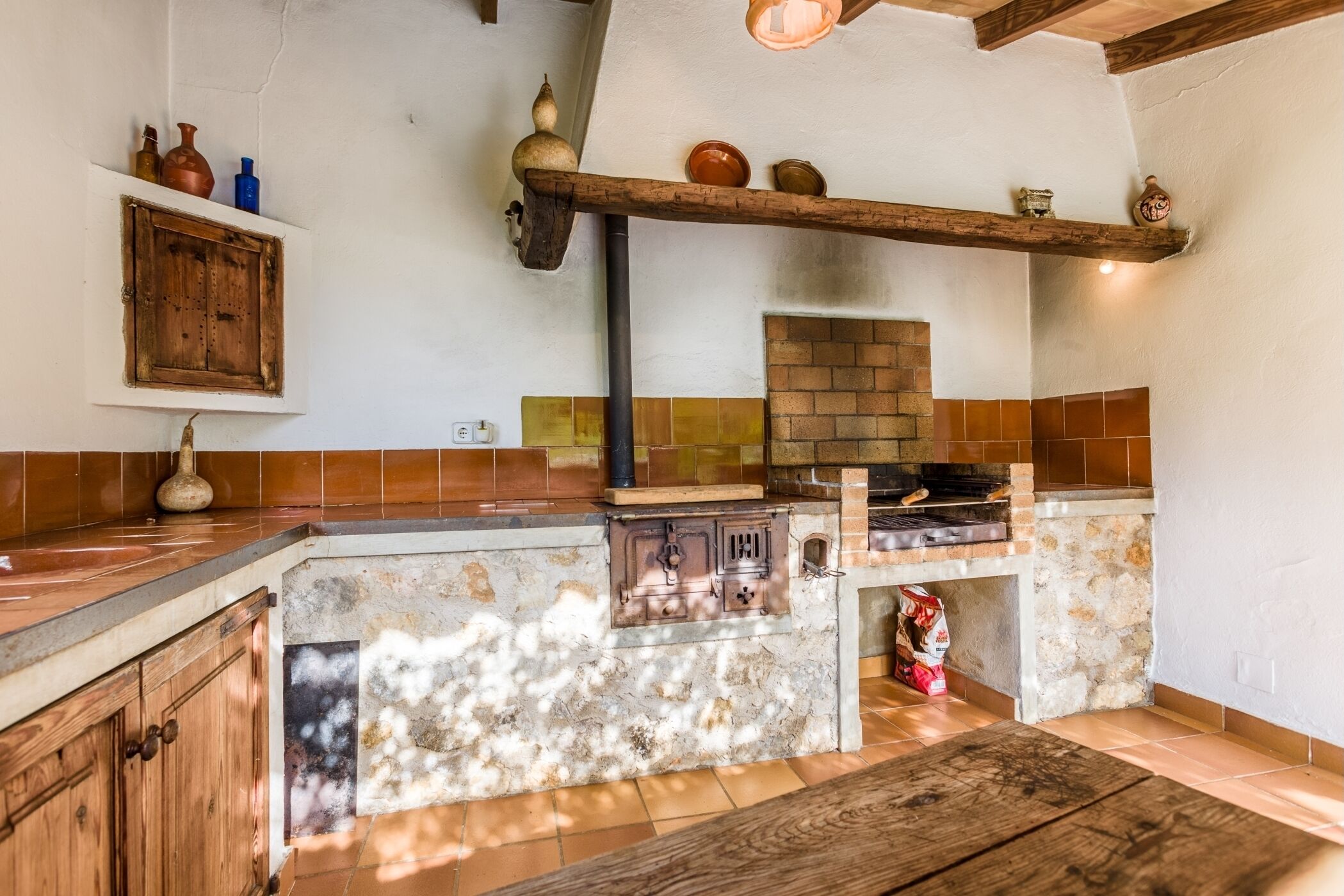 A rustic kitchen with a brick oven, wooden cabinets, and a stone island.