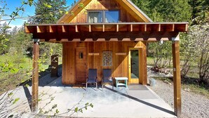 A wooden cabin with a porch, two chairs, and a small table. - Adeline - cute Mazama meadow cabin with sauna (Mazama)