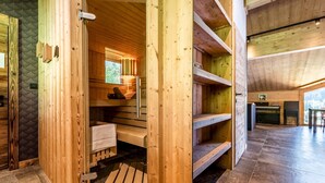 Una sauna de fusta amb una banca, una taula petita i un seient.
