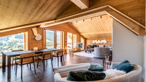 Un ampli espai tipus loft amb sostre alt, bigues de fusta, zona de menjador i un racó agradable per seure amb un sofà i coixins.
