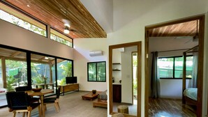 Un soggiorno moderno con zona pranzo, ampie finestre e soffitto in legno.
