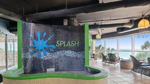 Ein Poolbereich mit einer Mosaik-Spritzwand und Blick aufs Meer.