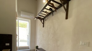 Un couloir avec un banc en bois, une plante en pot et une échelle appuyée contre le mur.