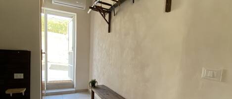 A hallway with a wooden bench, a potted plant, and a ladder against the wall.