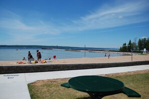 A beach with a green table and chairs, a sandy shore, and a clear blue sky. - If you love water & outdoor activities this is the place for you!! (Indian River)