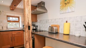 Une cuisine avec des meubles de rangement en bois, un plan de travail, une bouilloire, un grille-pain et un rouleau à pâtisserie jaune.
