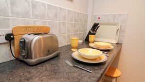 Un plan de travail de cuisine avec un grille-pain, des assiettes, des tasses et un bloc à couteaux.