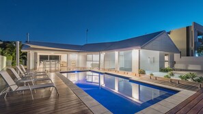 A modern outdoor pool area with lounge chairs and a covered seating area. - Wesley Court No. 21 Noosa Sound (Noosa Heads)
