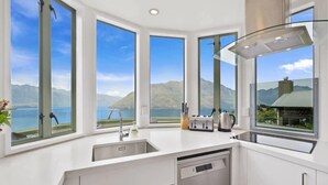 A modern kitchen with large windows offering a view of mountains and a lake. - Ruby's Fernhill Vista (Queenstown)