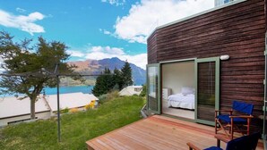 A wooden cabin with a glass door leading to a bedroom with a bed and a chair. - Ruby's Fernhill Vista (Queenstown)