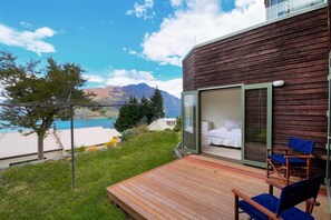 A wooden cabin with a glass door leading to a bedroom with a bed and a chair.