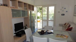 A compact living space with a kitchenette, a dining area, and a seating area with a view of the outdoors.