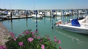 A marina with multiple boats docked at piers, surrounded by calm water and greenery.