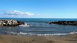 A beach with rocky breakwaters and calm waves.