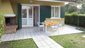 A patio with a brick fireplace, a table with chairs, and a window with shutters.