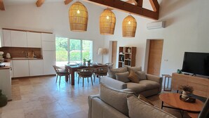 A spacious living area with a large sofa, a dining table, and a kitchen in the background.