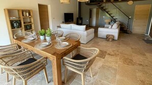 A dining area with a wooden table set for four, surrounded by wicker chairs.