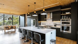 A modern kitchen with a central island, bar stools, and stainless steel appliances.