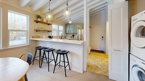 Una cocina moderna con barra, una mesa de comedor y una lavadora.
