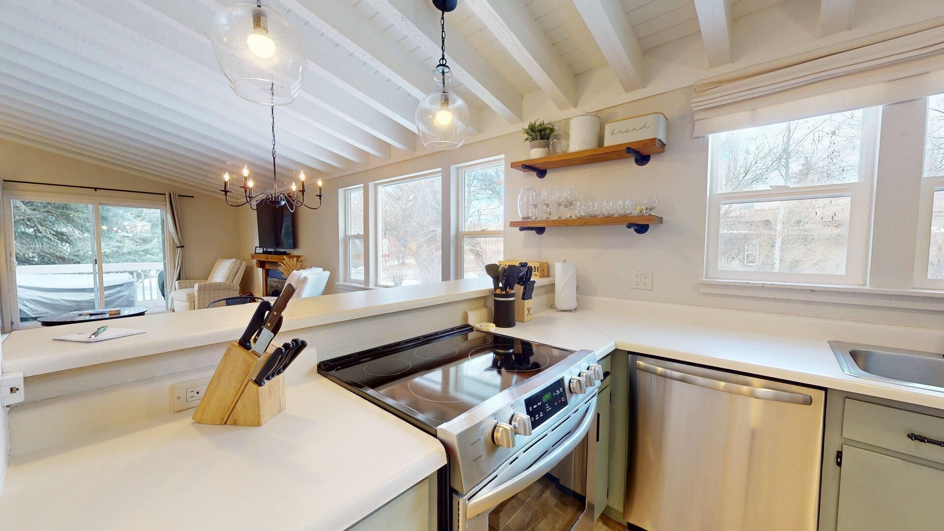 A modern kitchen with a central island, stainless steel appliances, and a hanging light fixture.