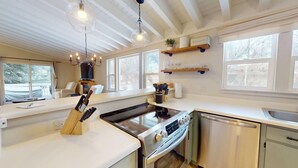 Una cocina moderna con una isla central, electrodomésticos de acero inoxidable y una lámpara colgante.