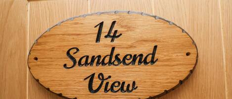 Un letrero de madera con el texto '14 Sandend View' en una puerta.