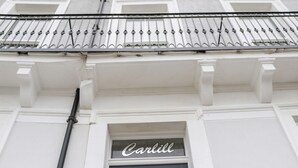 A building facade with a black door and a sign above it that reads "Carlill". - Sandsend View (Whitby)