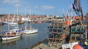 A harbor with boats docked and fishing gear on the shore. - Sandsend View (Whitby)