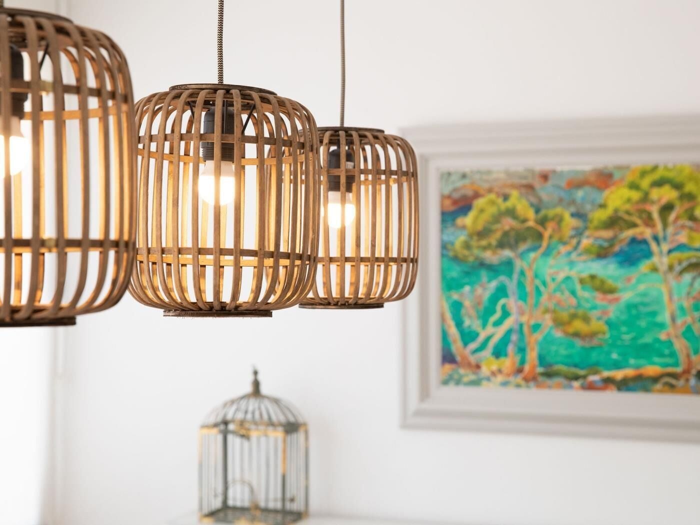 A room with three hanging wooden light fixtures and a framed painting on the wall.