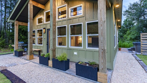 A two-story building with multiple windows and a covered patio area. - Kitty Hawk Reserve OBX Tiny House! Hot Tub & Beach included! (Kitty Hawk)