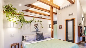 A bedroom with a bed, bedside table, and a wall-mounted plant. - Kitty Hawk Reserve OBX Tiny House! Hot Tub & Beach included! (Kitty Hawk)